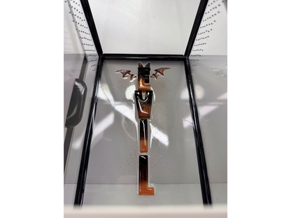 Schriftzug aus Epoxidharz in einem Terrarium für baumbewohnende Spinnen in schwarz und rot mit Flügeln und Hörnchen